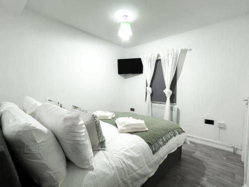 a white bedroom with a bed and a television at Studio with Bathroom and Kitchen 20 minutes from Central London in London