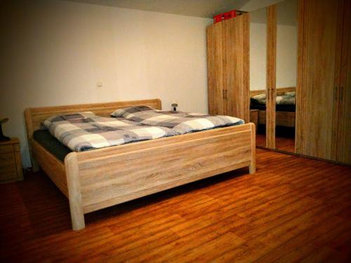 ein Holzbett in einem Zimmer mit Spiegel in der Unterkunft Ferienhof Nustede in Wardenburg