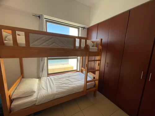 um quarto beliche com 2 beliches e uma janela em Sea View Beach Hostel - Walk to Beach - Metro Station - Pool em Dubai