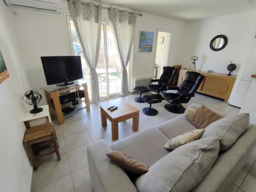 - un salon avec un canapé et une télévision dans l'établissement Appartement T3 avec piscine, climatisation, wifi et garage, à Collioure