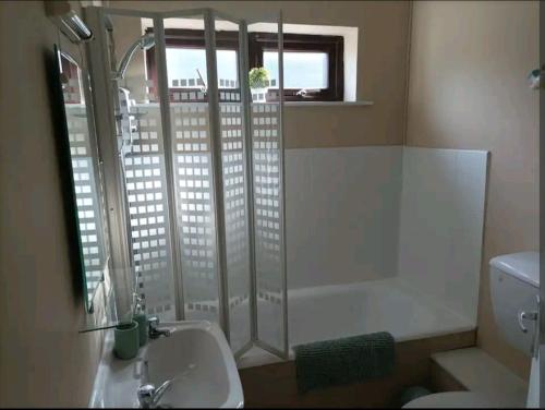 baño con bañera, lavabo y ventana en The Croft Apartment, en Westport