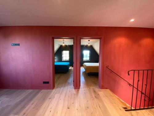 a room with red walls and a bedroom with a bed at Vakantiehuis The Nuthouse in Roeselare