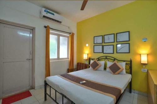 卡蘭古特的住宿－Luxury 3 bhk beach apartment Calangute，一间卧室设有一张黄色墙壁和窗户的床