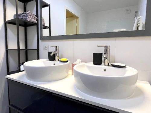 une salle de bain blanche avec deux lavabos et un miroir dans l'établissement Le Penthouse de Levallois, à Levallois-Perret