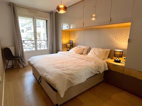 une chambre avec un grand lit et une fenêtre dans l'établissement Le Penthouse de Levallois, à Levallois-Perret