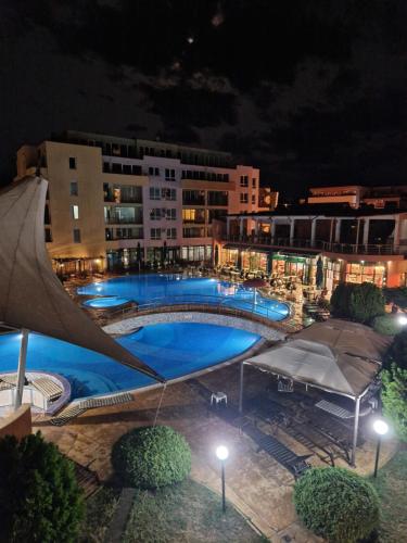 a large swimming pool at night in a city at Pool View Apartment, Sunny Beach Resort in Sunny Beach