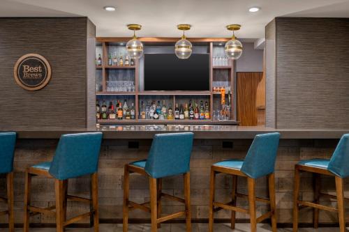 un bar avec des chaises bleues et une télévision dans l'établissement Four Points by Sheraton Chicago Westchester/Oak Brook, à Westchester
