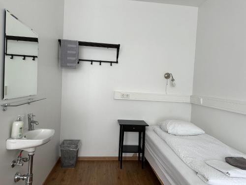 - une salle de bains blanche avec un lit et un lavabo dans l'établissement Kanslarinn Hostel, à Hella