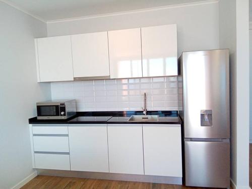 a kitchen with white cabinets and a stainless steel refrigerator at Praia Encantada in Porto Santo
