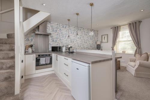 a kitchen with white cabinets and a counter top at Brunswick Cottage in Penrith