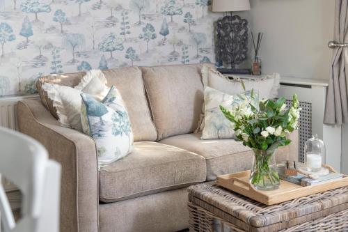a living room with a couch and a table with a vase of flowers at Brunswick Cottage, Penrith, The Lake District in Penrith