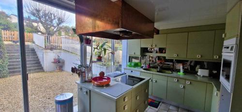 une cuisine avec des placards verts et une grande fenêtre dans l'établissement Chez Marcelle et Claude, à Belleville-sur-Meuse