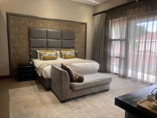 a bedroom with a large bed with a chair and a couch at One O Eight Boutique Hotel in Benoni