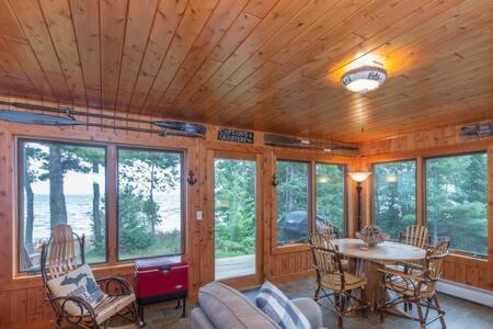 sala de estar con mesa, sillas y ventanas en Lake Superior Cabin with Fireplace Snowmobile Trails, en Paradise