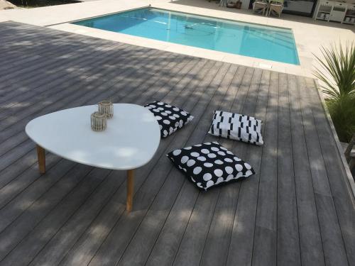 - une table et des oreillers sur une terrasse à côté de la piscine dans l'établissement Charmante dépendance, à Arès