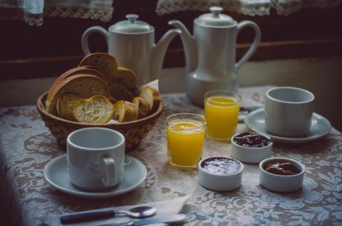 Una mesa con una cesta de pan y vasos de jugo de naranja. en Hostería La Pergola, en Villa Serranita