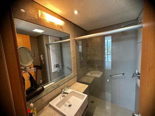 a bathroom with a sink and a shower and a mirror at Flat no Jade Hotel in Brasilia