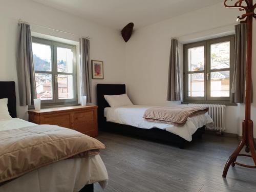 a bedroom with two beds and two windows at Locanda La Pignatta in Arogno