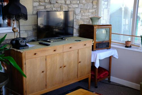 a tv sitting on a dresser with a television at Quirky mid century themed holiday home in Shepton Mallet