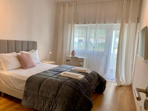 Comfortable bedrooms in apartment with river view في ألمادا: غرفة نوم بسرير ونافذة كبيرة