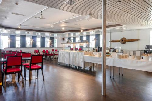 un restaurante con mesas blancas y sillas rojas en Air Hotel Nummela, en Nummela