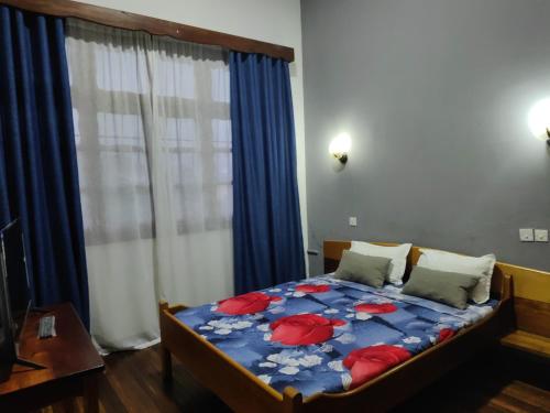 a bedroom with a bed with a blue comforter and a window at Hôtel Diamant Antsirabe in Antsirabe