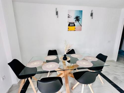Playa Dona Sofia Bella في فوينخيرولا: غرفة طعام مع طاولة زجاجية وكراسي سوداء