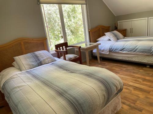 a bedroom with two beds and a table and a window at Casa Viña in Valdivia