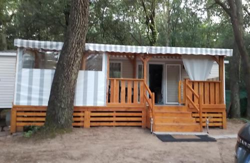 a house with a porch and a tree at Mobil home Aventura 6-8 personnes tout confort in Saint-Brevin-les-Pins