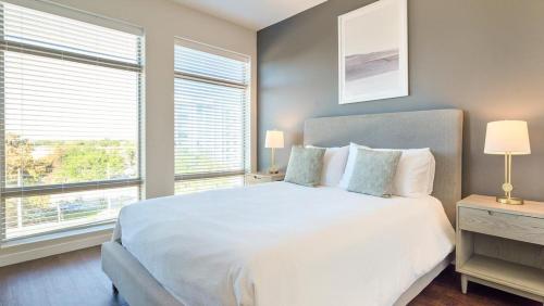 1 dormitorio con 1 cama blanca grande y 2 ventanas en Landing - Modern Apartment with Amazing Amenities (ID7550X75), en Orlando
