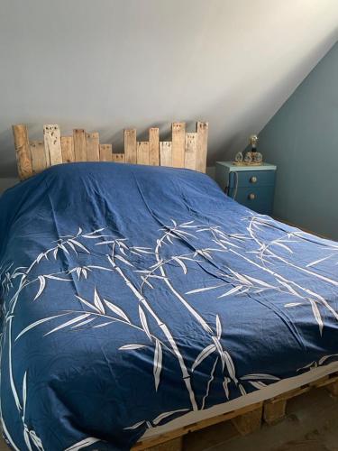 a bed with a blue comforter with branches on it at Chambre étape only femme in Pédernec