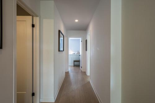 a hallway with white walls and wooden floors at La totale : luxury 3 BR at the mountain in Mont-Tremblant