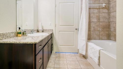 La salle de bains est pourvue d'une baignoire, d'un lavabo et d'une douche. dans l'établissement Landing - Modern Apartment with Amazing Amenities (ID8209X45), à Houston