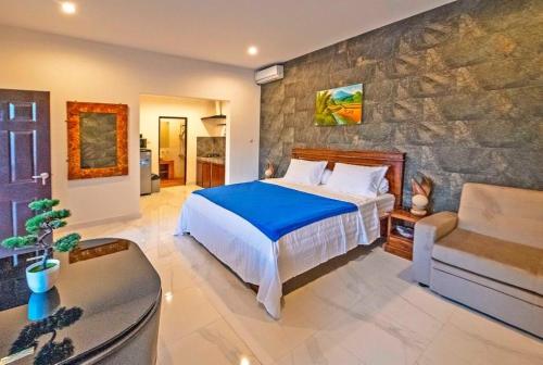 a bedroom with a bed and a stone wall at Serendipity Bali in Sanur