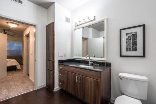 a bathroom with a sink and a toilet and a mirror at Landing - Modern Apartment with Amazing Amenities (ID5045X8) in San Antonio