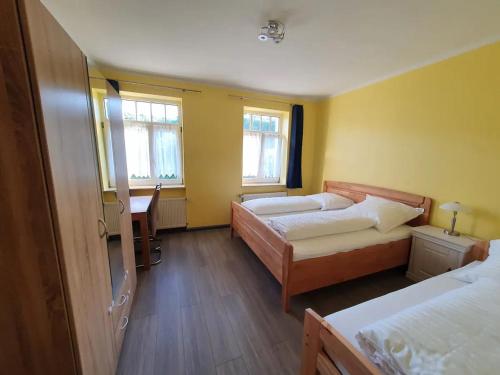 a bedroom with two beds and a desk and two windows at Schöne Wohnung in Eisenach in Eisenach