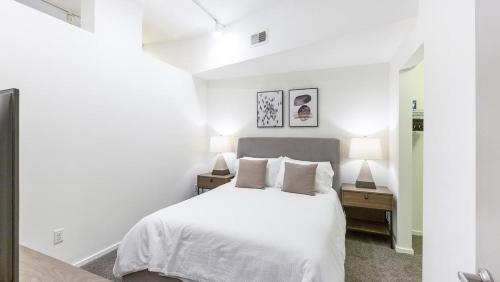 a white bedroom with a white bed and two lamps at Landing - Modern Apartment with Amazing Amenities (ID8398X30) in Omaha