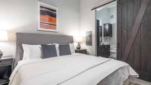 a white bedroom with a large white bed with two pillows at Landing - Modern Apartment with Amazing Amenities (ID6650X47) in Fort Worth