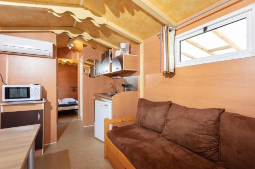 a living room with a couch in a tiny house at Camping Les Amandiers in Castelnau-de-Guers
