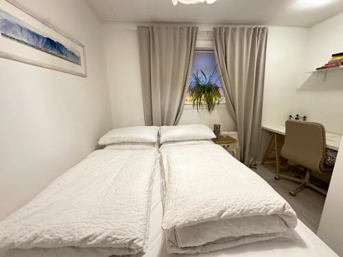 a white bed in a bedroom with a desk and a window at Apartment in Reykjavikurvegur - Birta Rentals in Hafnarfjördur