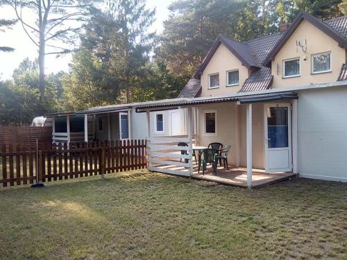 une maison avec une clôture et une table sur une terrasse dans l'établissement Domek 2, à Dębki