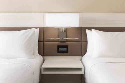 two beds with white pillows and a table between them at AC Hotel by Marriott Jacksonville St Johns Town Center in Jacksonville