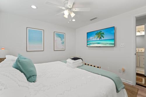 a white bedroom with a bed and a ceiling fan at Wine Down, Heated Saltwater Pool in Jacksonville Beach