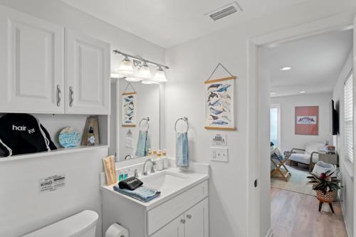 ein weißes Badezimmer mit einem Waschbecken und einem Spiegel in der Unterkunft Wine Down, Heated Saltwater Pool in Jacksonville Beach