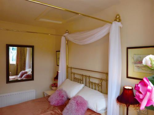 um quarto com uma cama de dossel e almofadas cor-de-rosa felpudas em Wood End Cottage em Slaithwaite