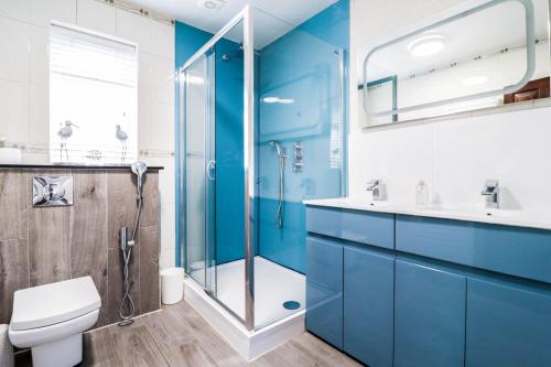 a blue bathroom with a shower and a toilet at Luxurious 5 Bed Property! in Woodley