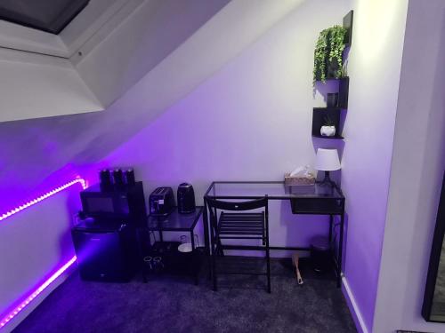 Cette chambre comprend un bureau et une table avec une lumière violette. dans l'établissement Hornet's Hideout, à Watford