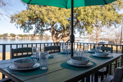 a wooden table with bowls and glasses and an umbrella at Family Lakefront Retreat in Granite Shoals