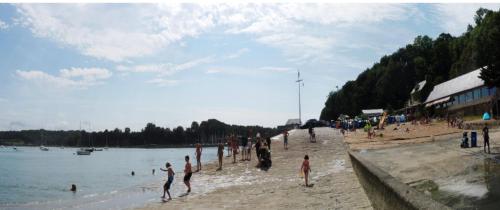 un grupo de personas en una playa cerca del agua en Kerfly, en Plouër-sur-Rance