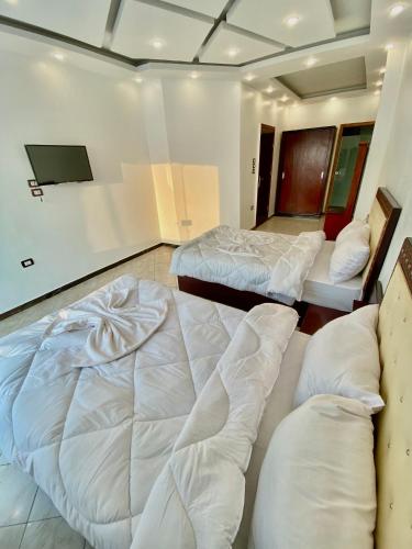 a room with two beds and a flat screen tv at Enjoy Giza Pyramids View in Cairo